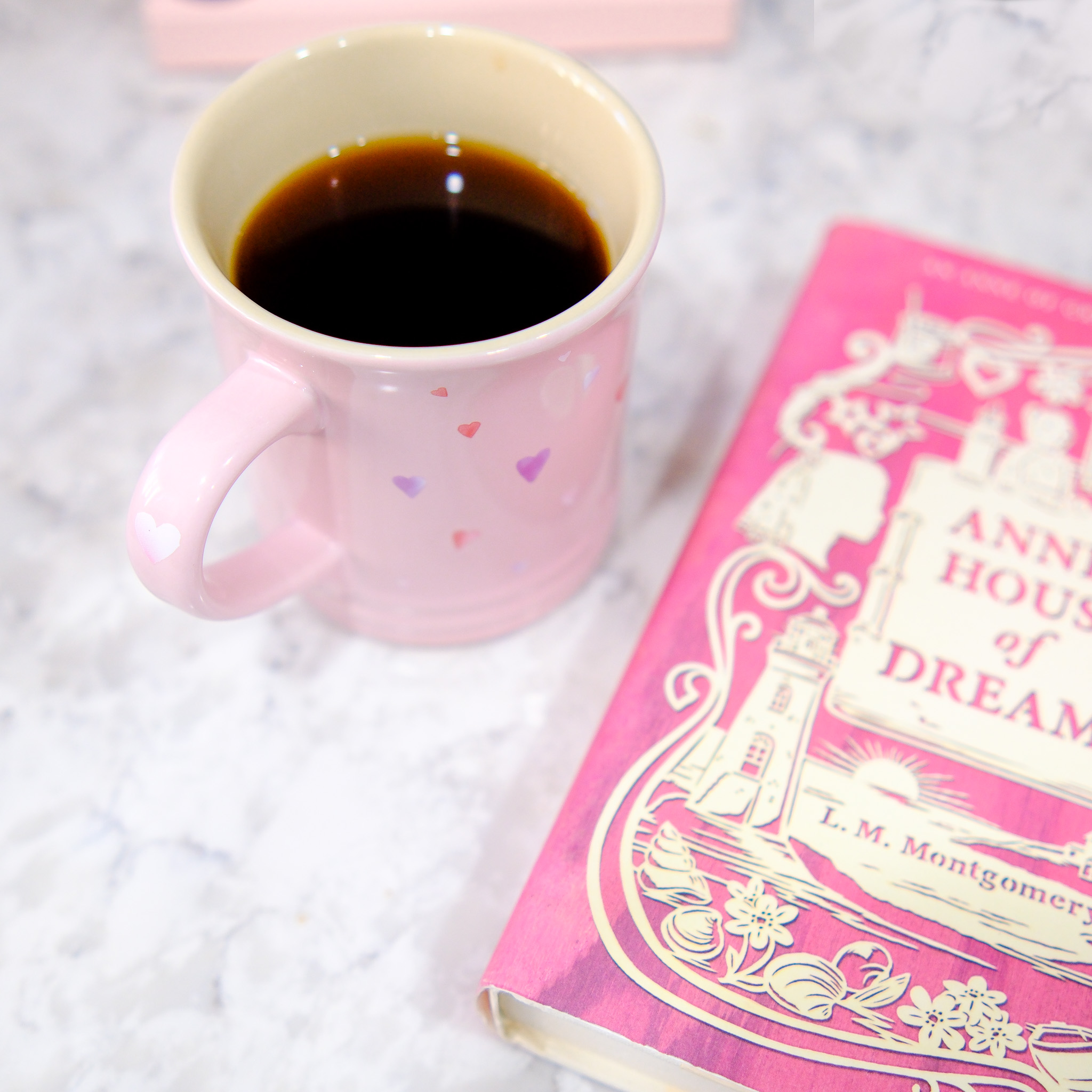 coffee in a pink mug next to a pink book